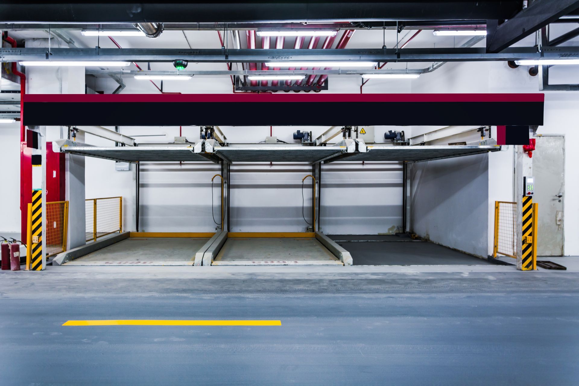 Multi-level automated car parking system in an indoor garage. Gray floors, red and yellow columns.