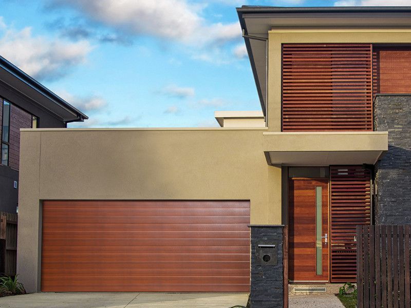 Modern house exterior with brown garage door, wooden shutters, and entry door.