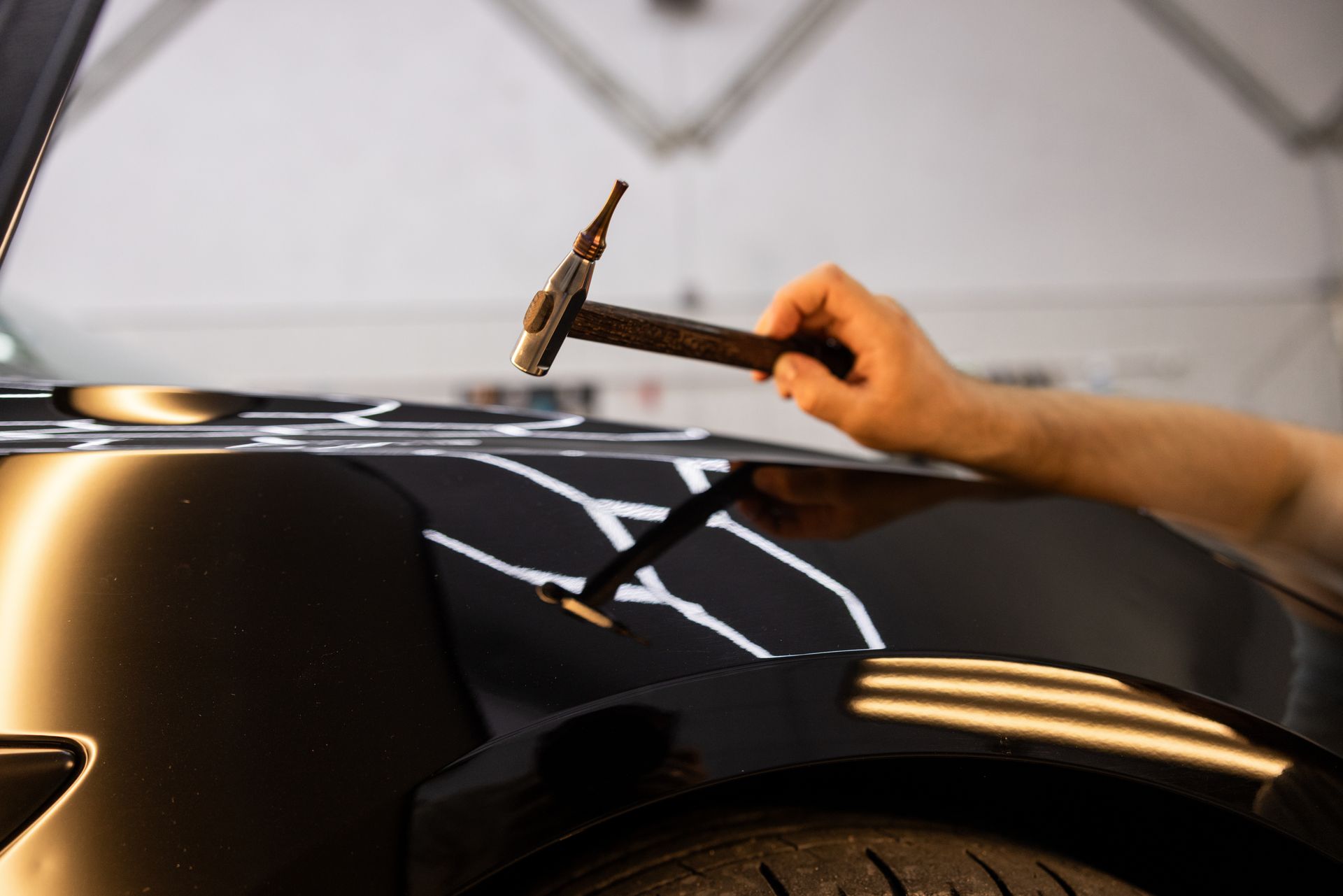 A technician using professional tools to repair vehicle body damage after a collision.