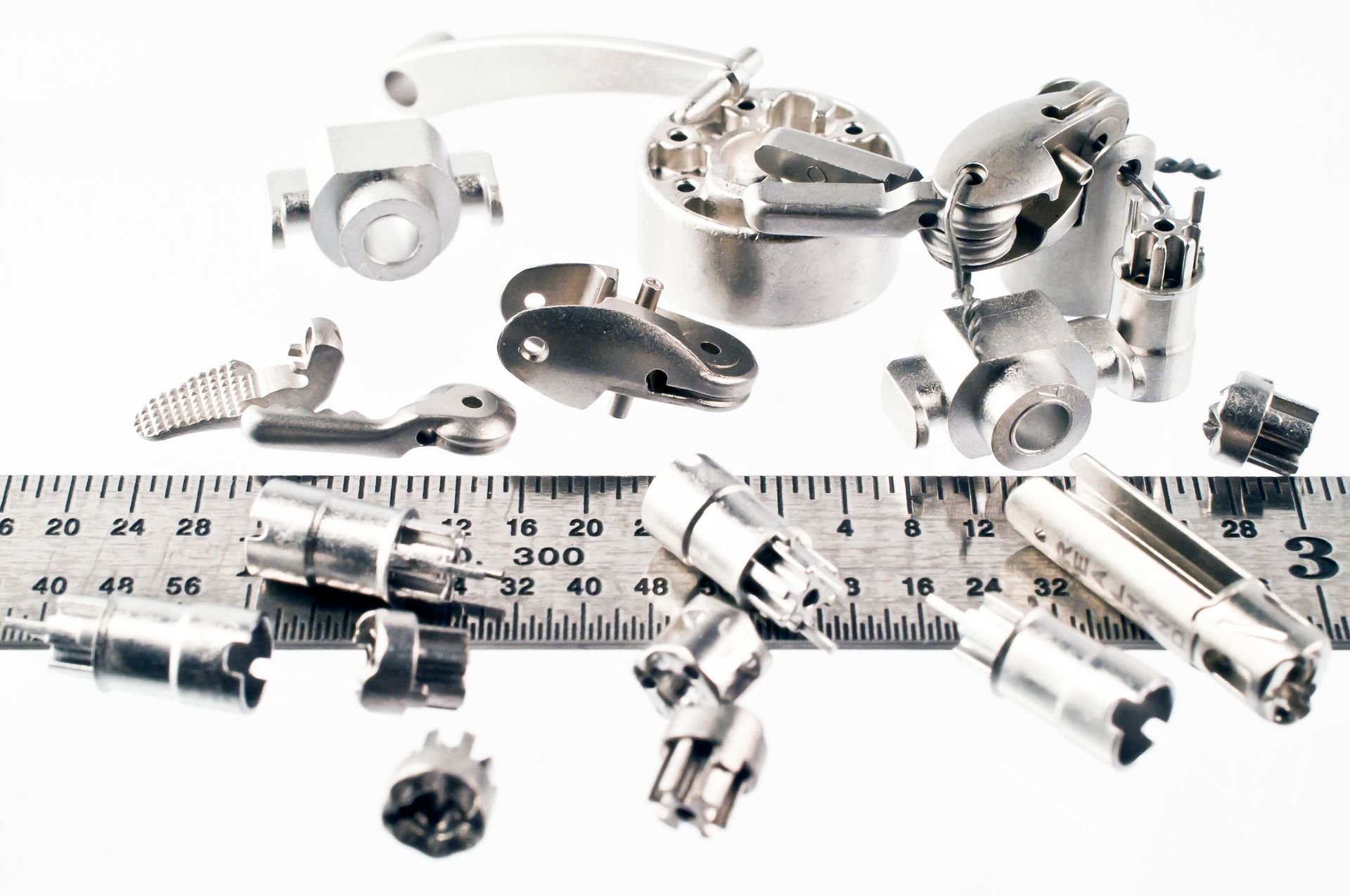 metal injection molded parts on ruler for scale
