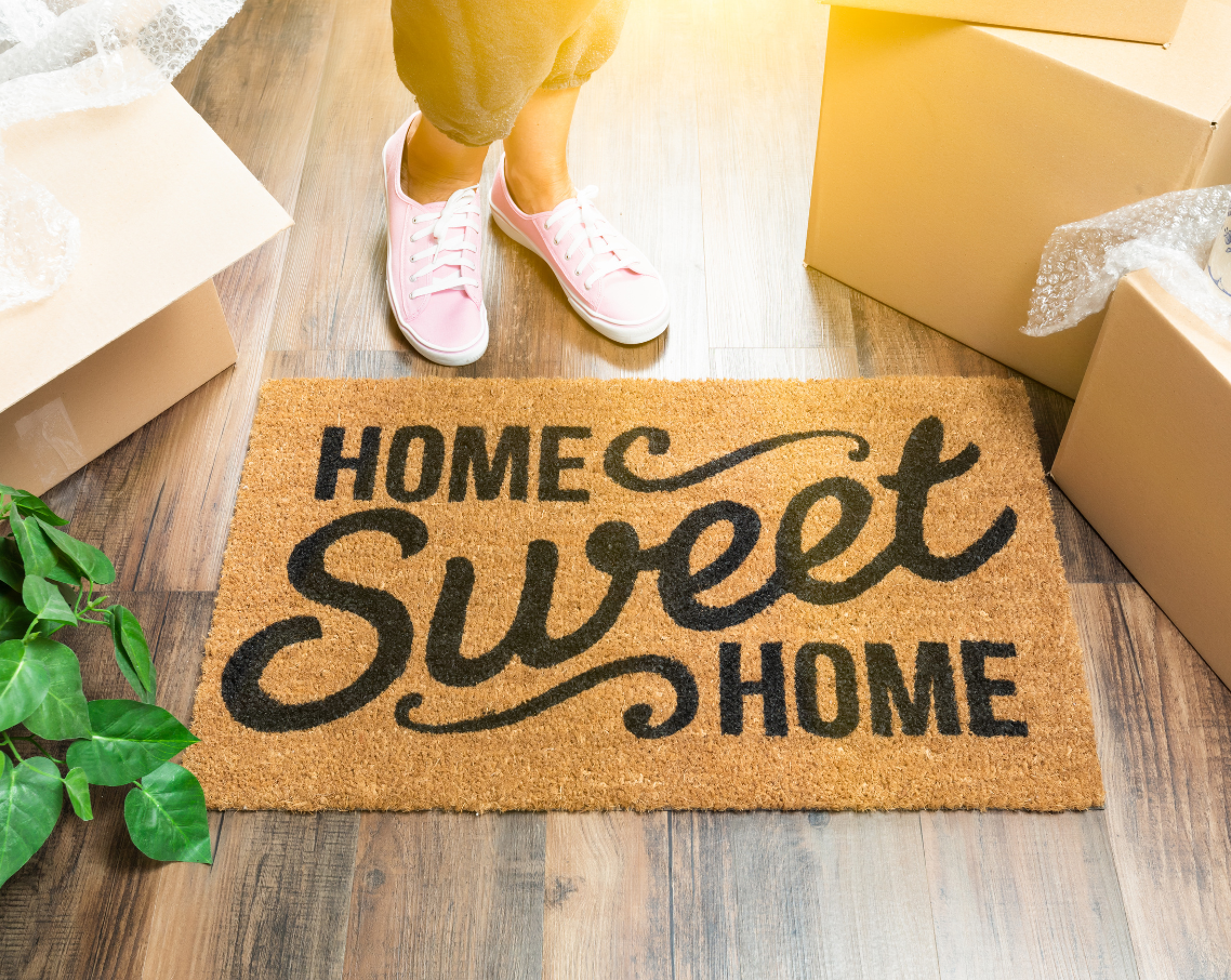 A person is standing on a door mat that says `` home sweet home ''.