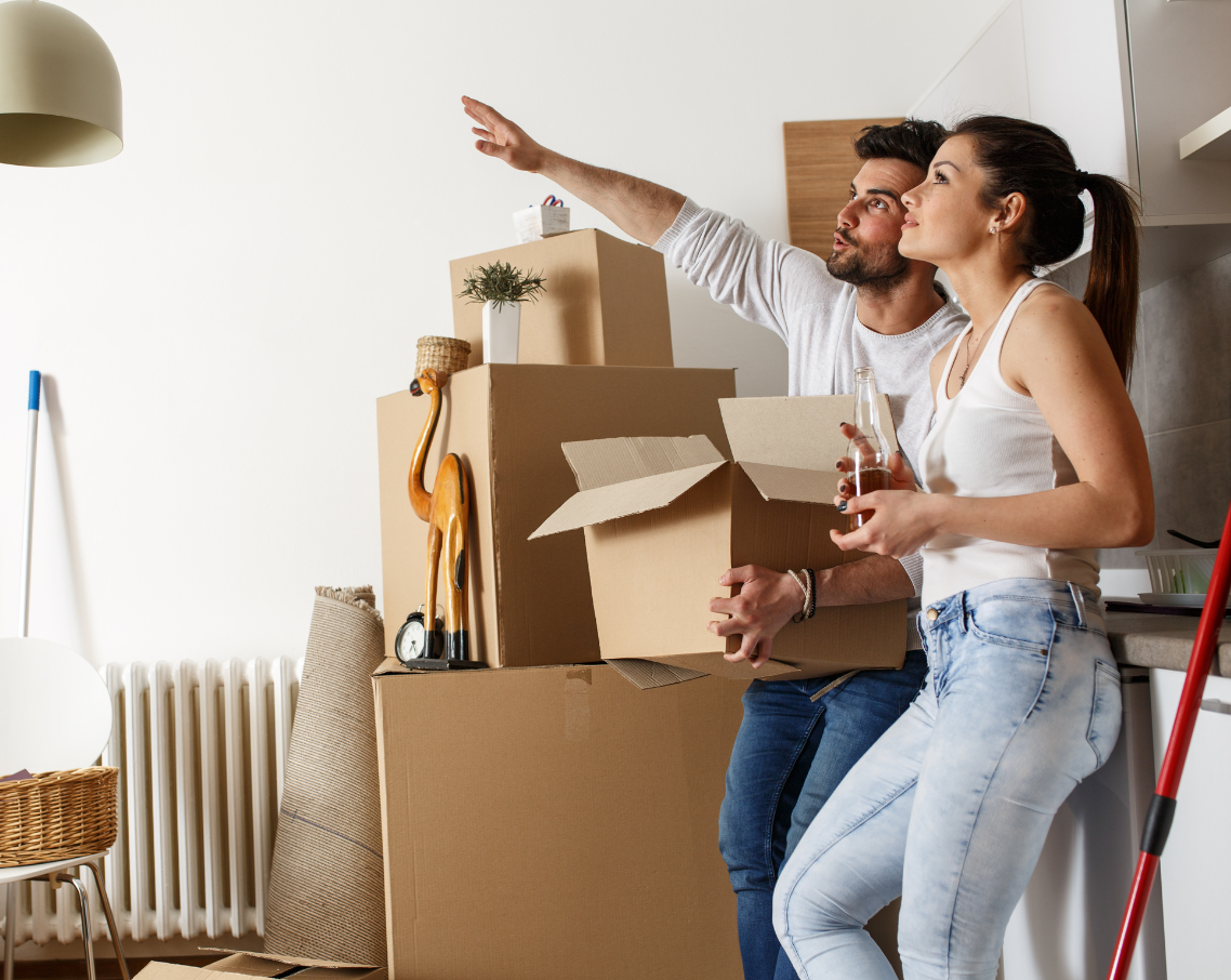 A man and a woman are standing in front of a pile of cardboard boxes.