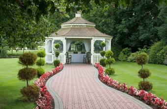 A white gazebo with a brick walkway leading to it