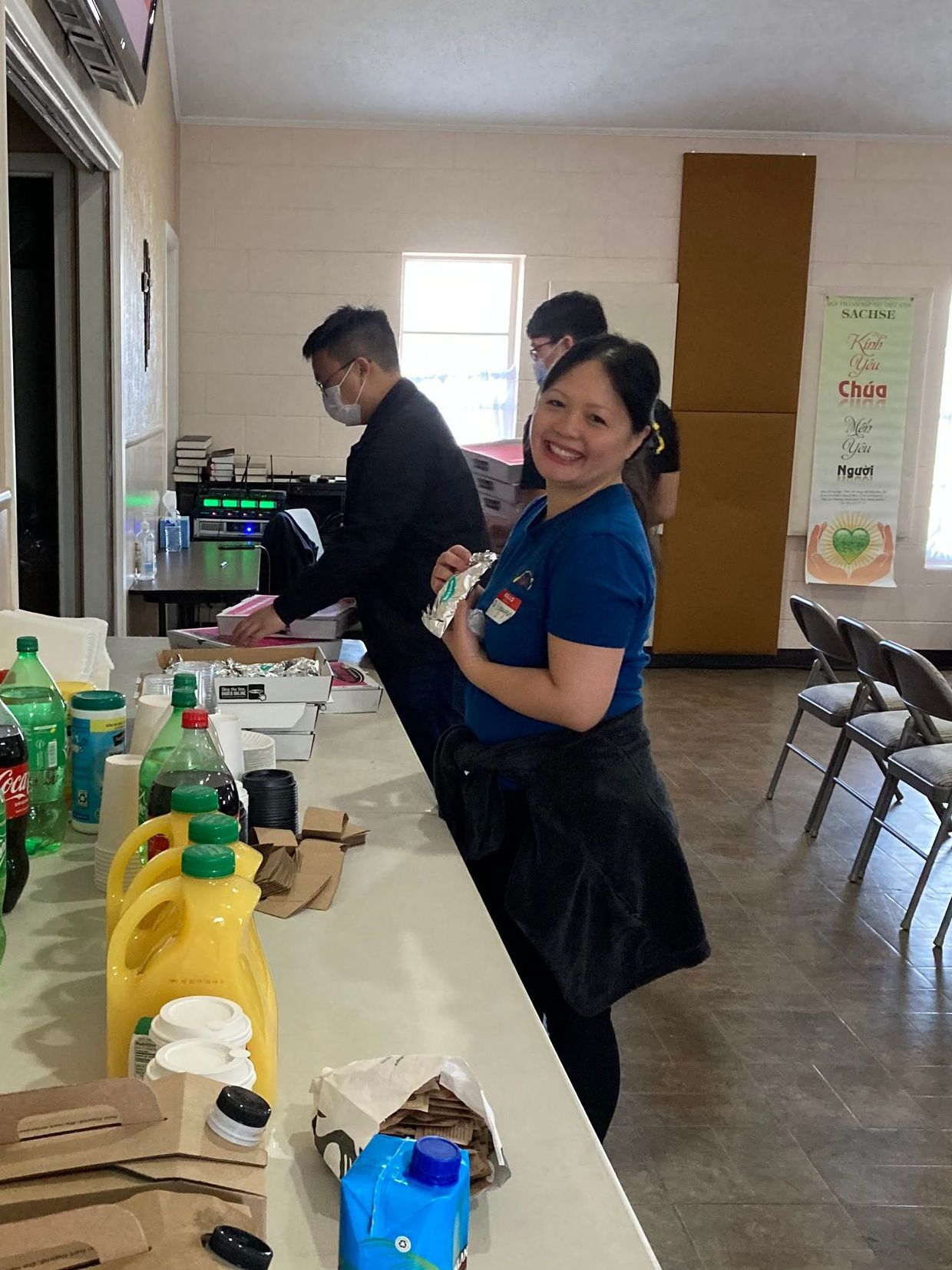 A woman is standing at a counter in a room with other people.