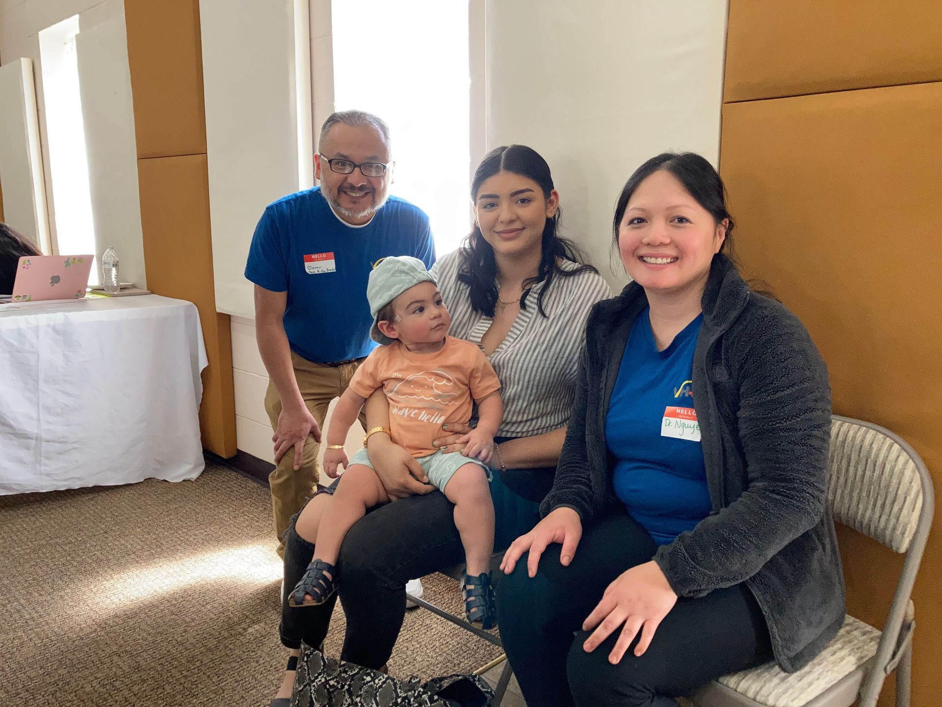 A group of people are sitting in chairs holding a baby.