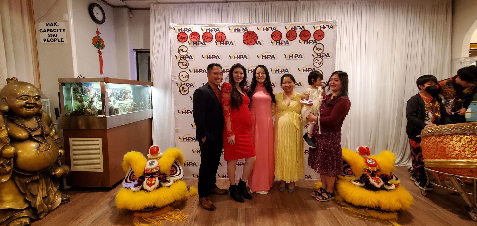 A group of people are posing for a picture in a room with lion dancers.