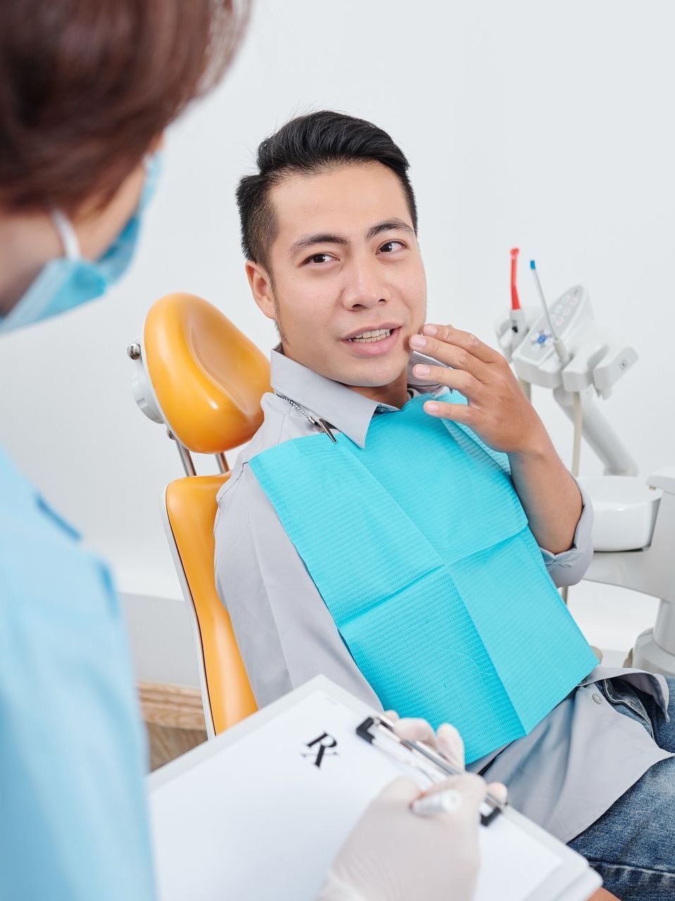 A man is sitting in a dental chair talking to a dentist.