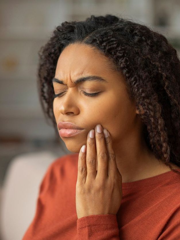 A woman is holding her face in pain because of a toothache.