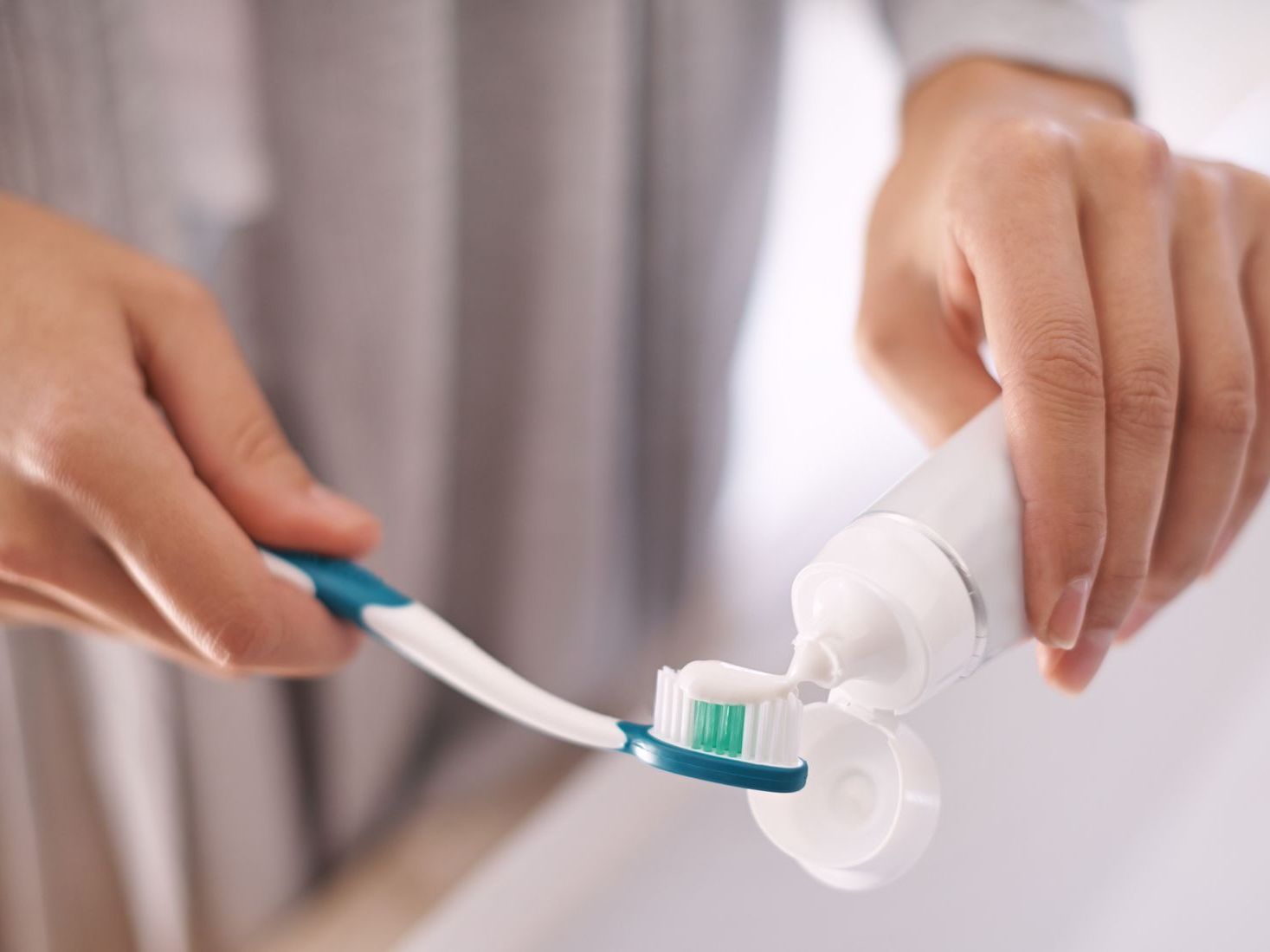 A person is putting toothpaste on a toothbrush.