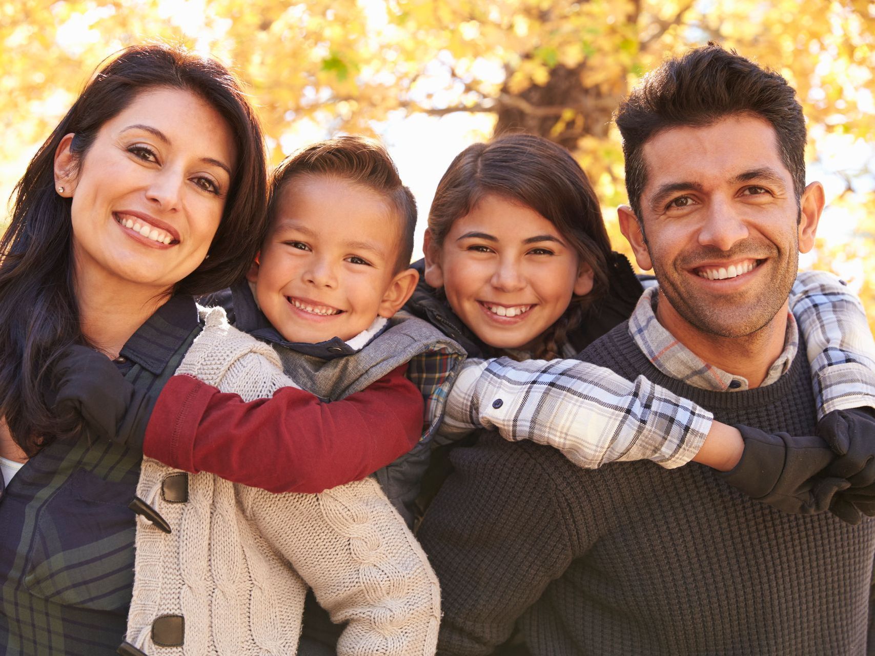 A family is posing for a picture in front of a tree.