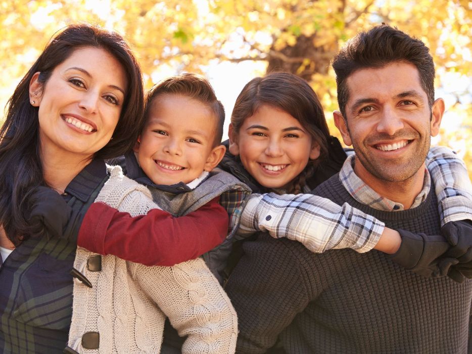 A family is posing for a picture in front of a tree.