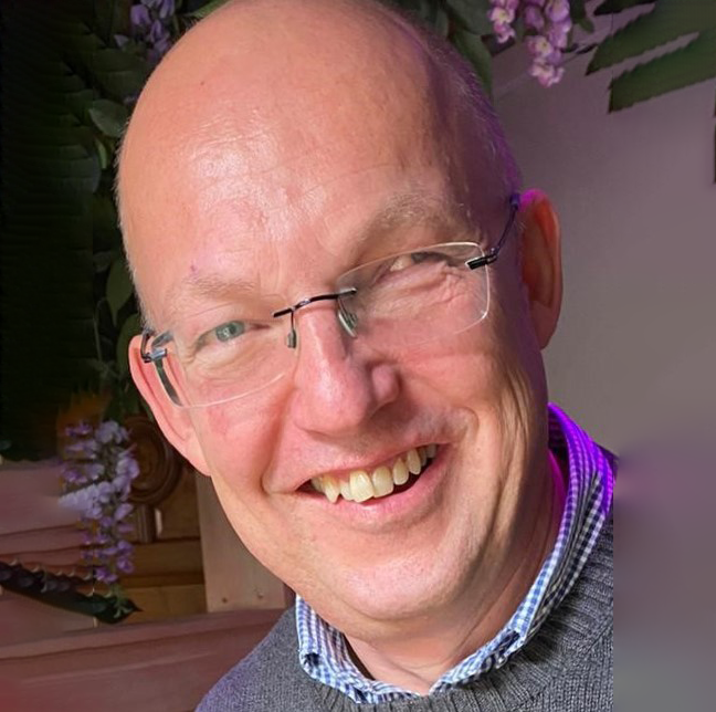 A bald man wearing glasses is smiling for the camera.