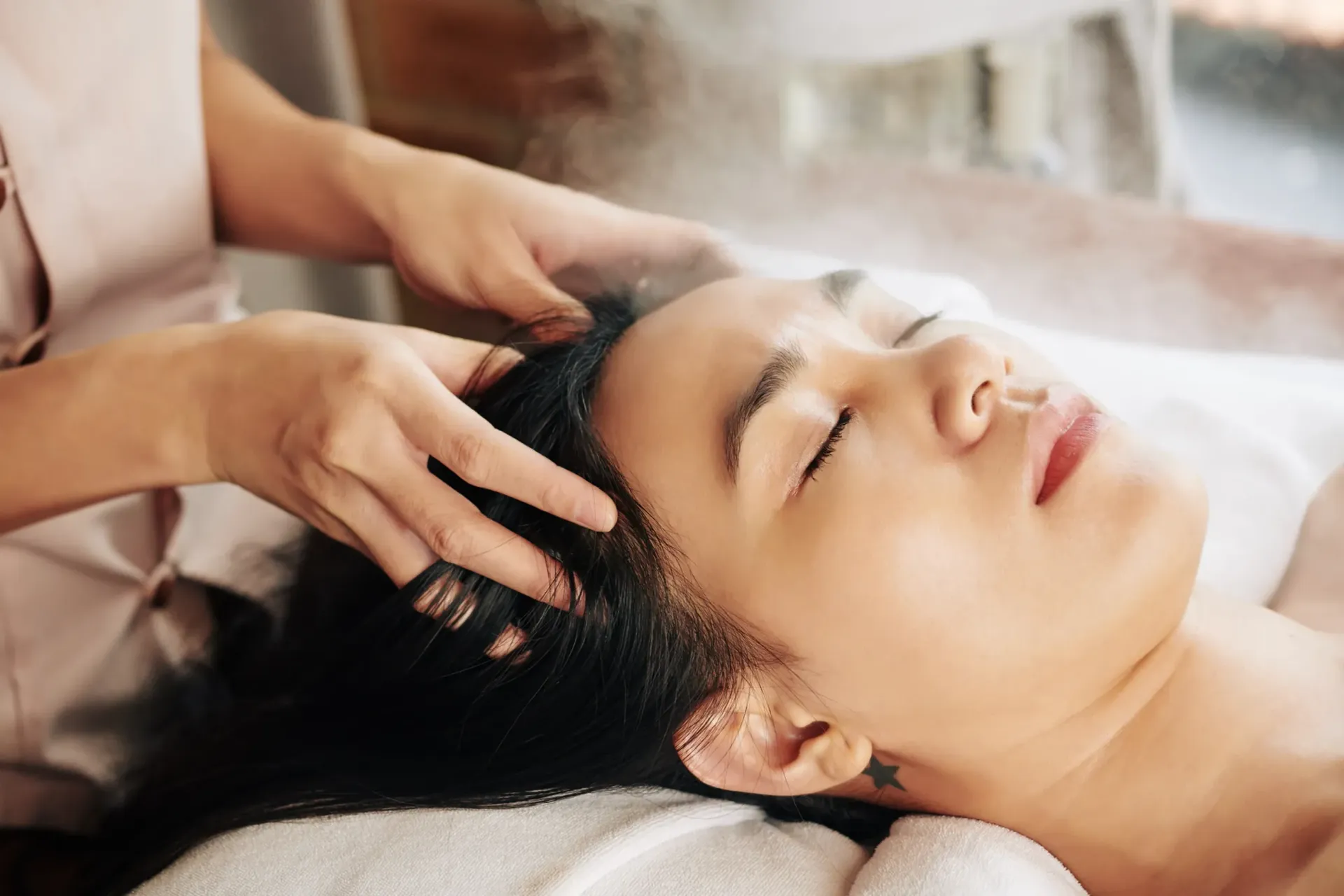 A woman is getting a head massage at a spa.