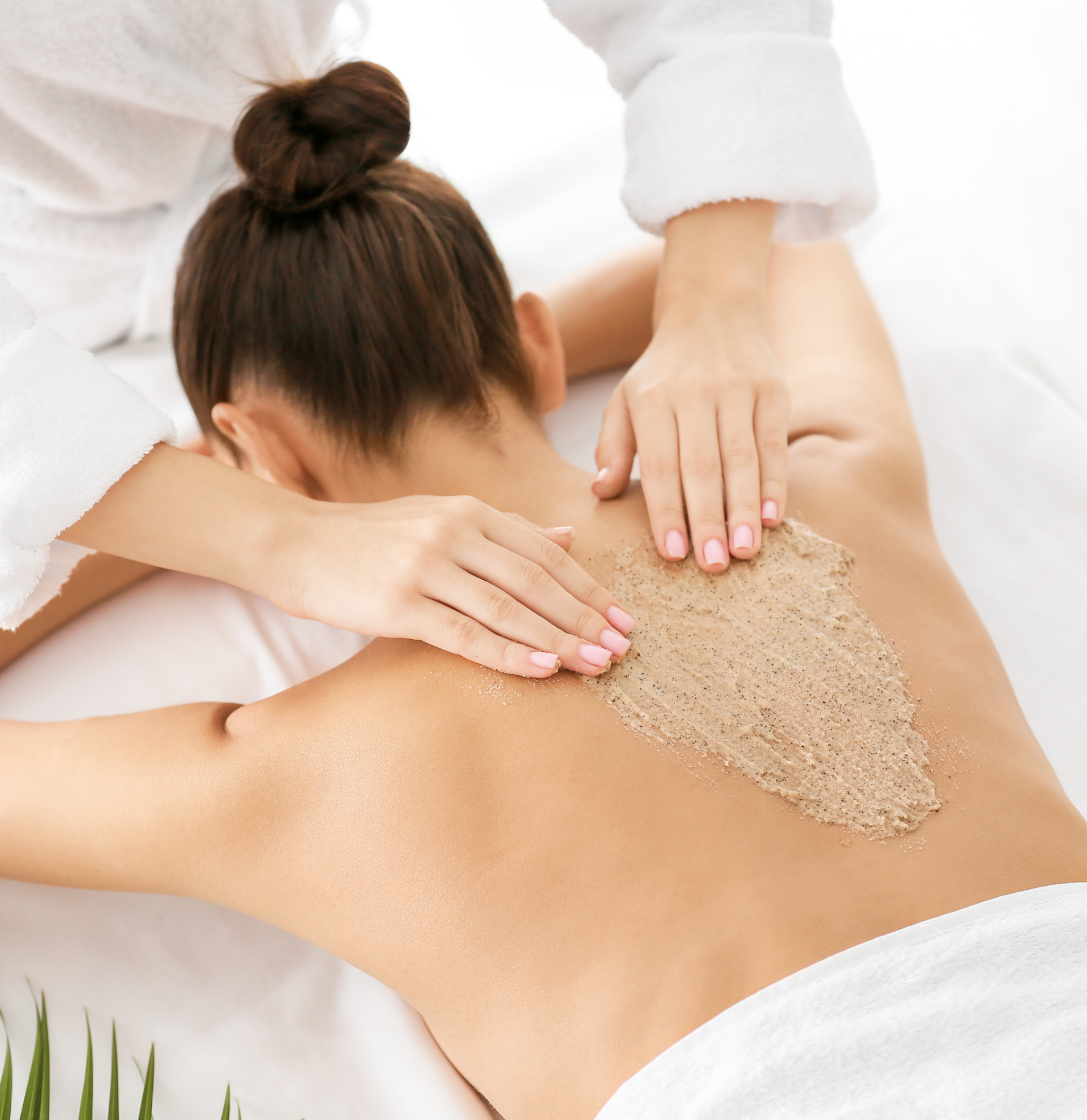 A woman is getting a massage with sand on her back
