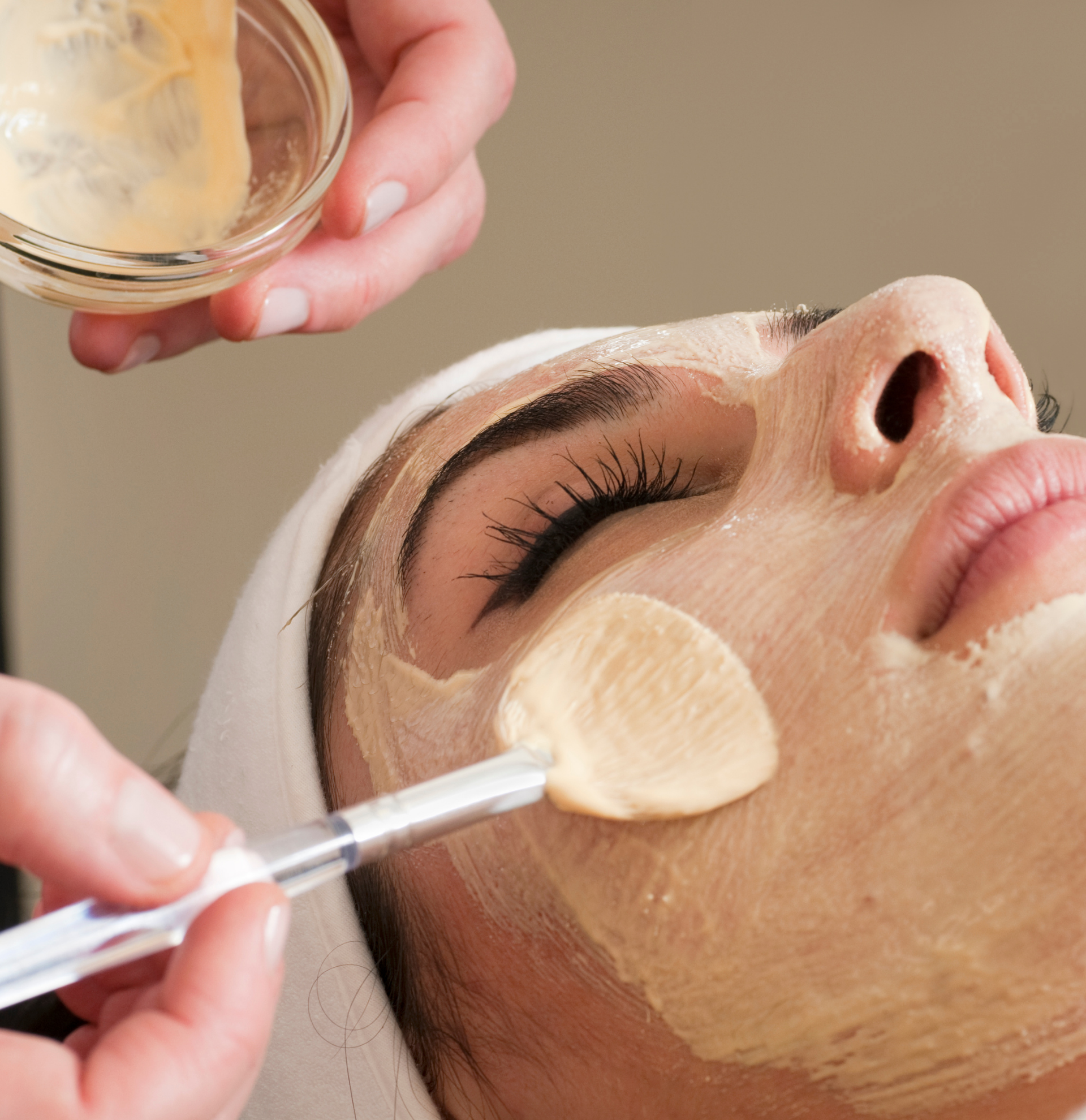 A woman is getting a facial treatment with a brush