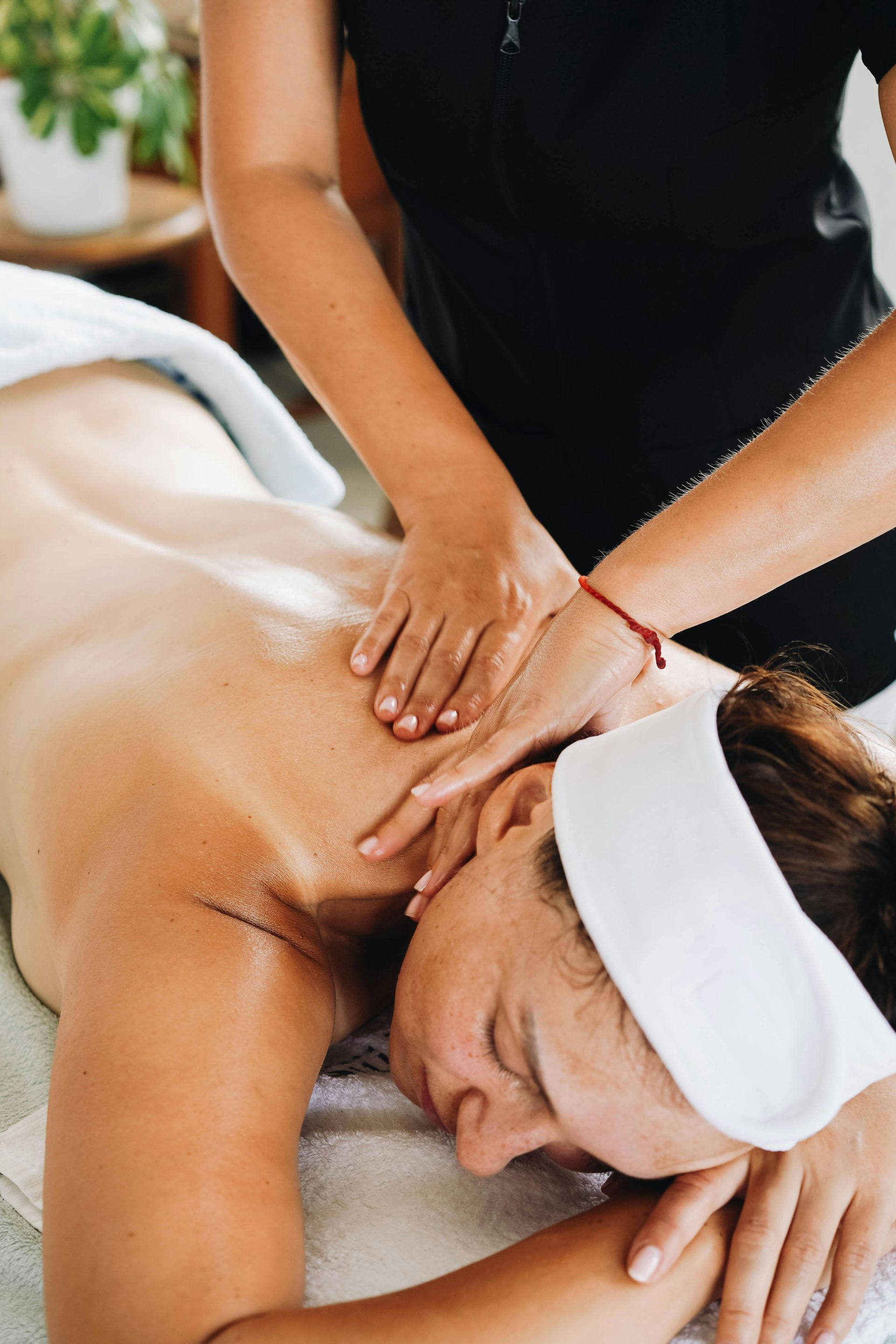 Woman laying on massage table with half of her back painted with a green seaweed mud mask for a body wrap treatment and back facial.