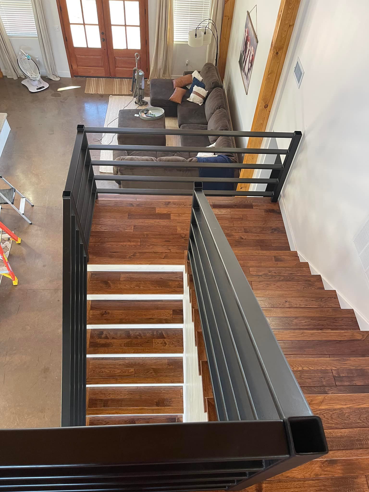 A wooden staircase with a metal railing leading up to a living room.