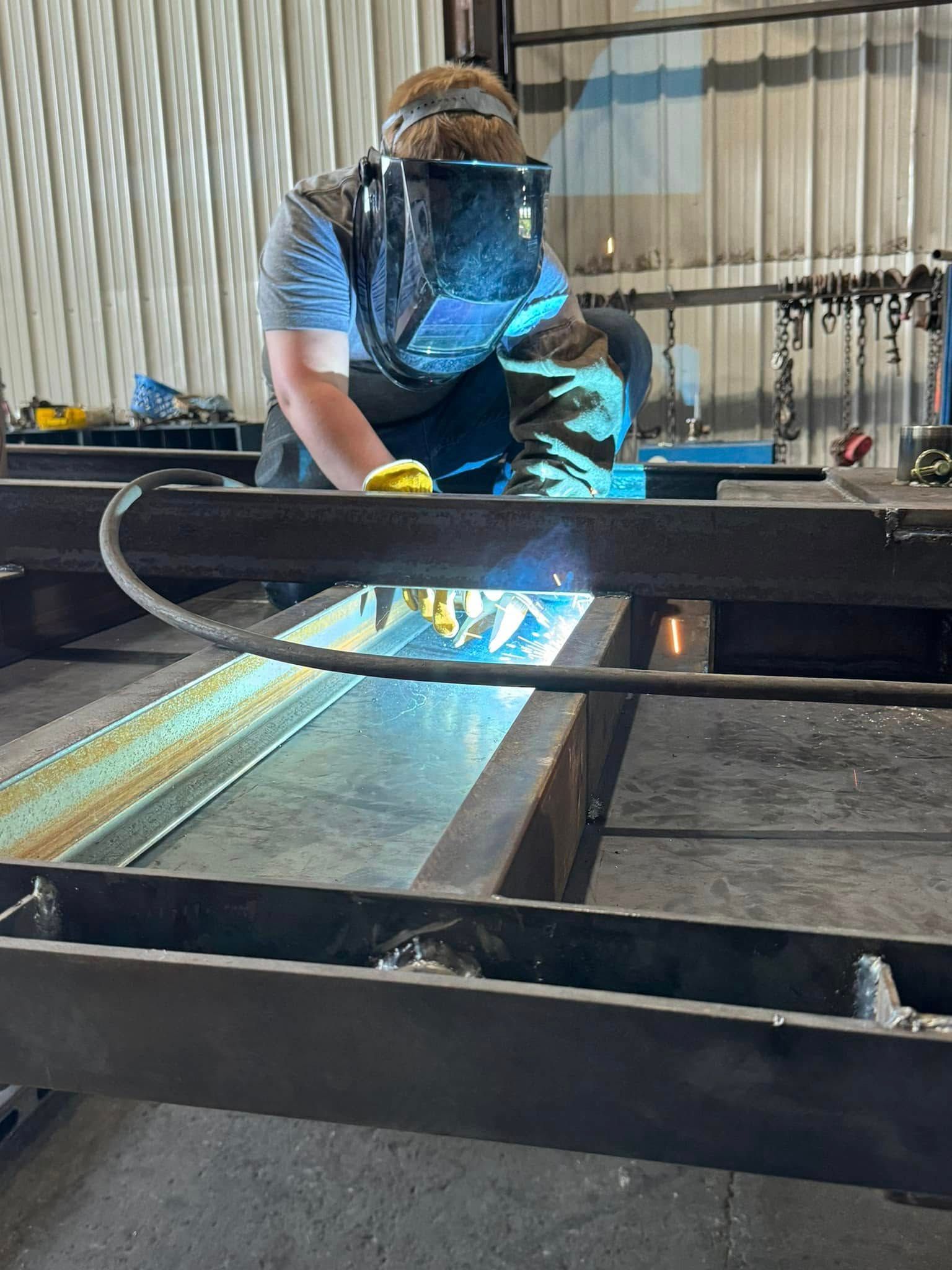 A man is welding a piece of metal in a factory.