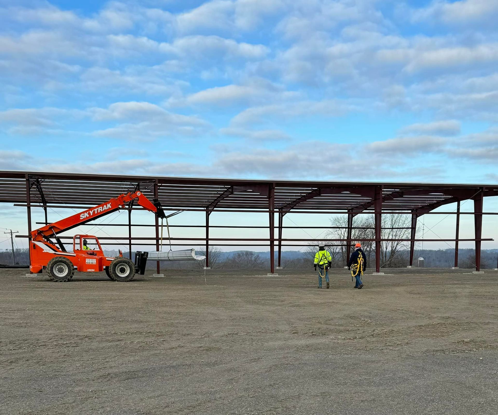 Two men are standing in front of a large building under construction.