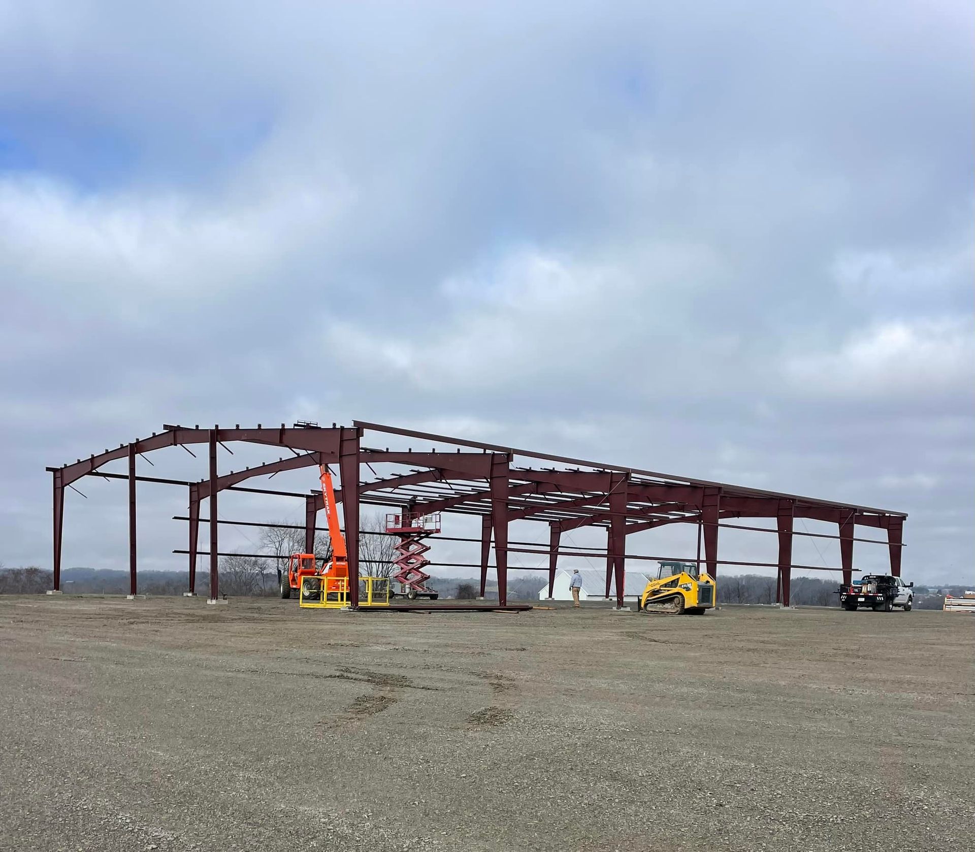 A large metal structure is being built in a dirt field.