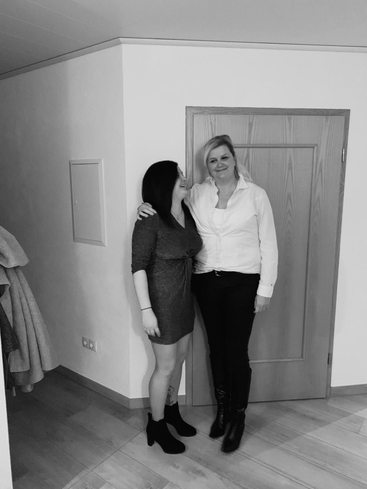 Eine Frau mit langen blonden Haaren lächelt vor einem schwarzen Hintergrund.