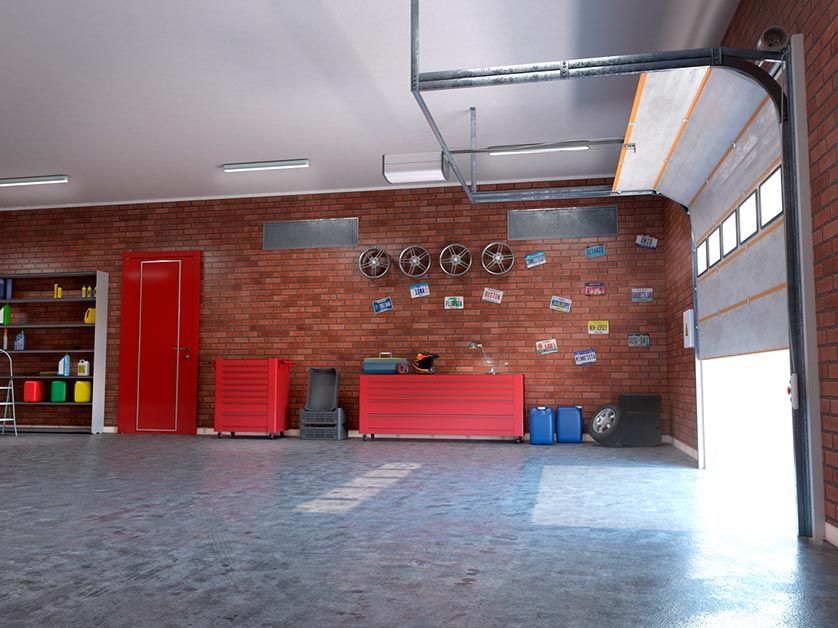 An empty garage with a brick wall and a garage door open.