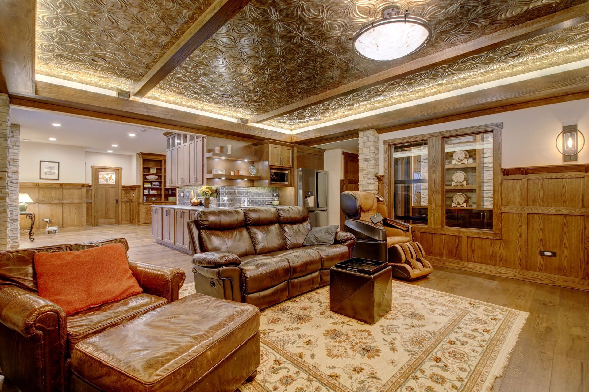 Open-concept living space with leather furniture, kitchen, and decorative ceiling.