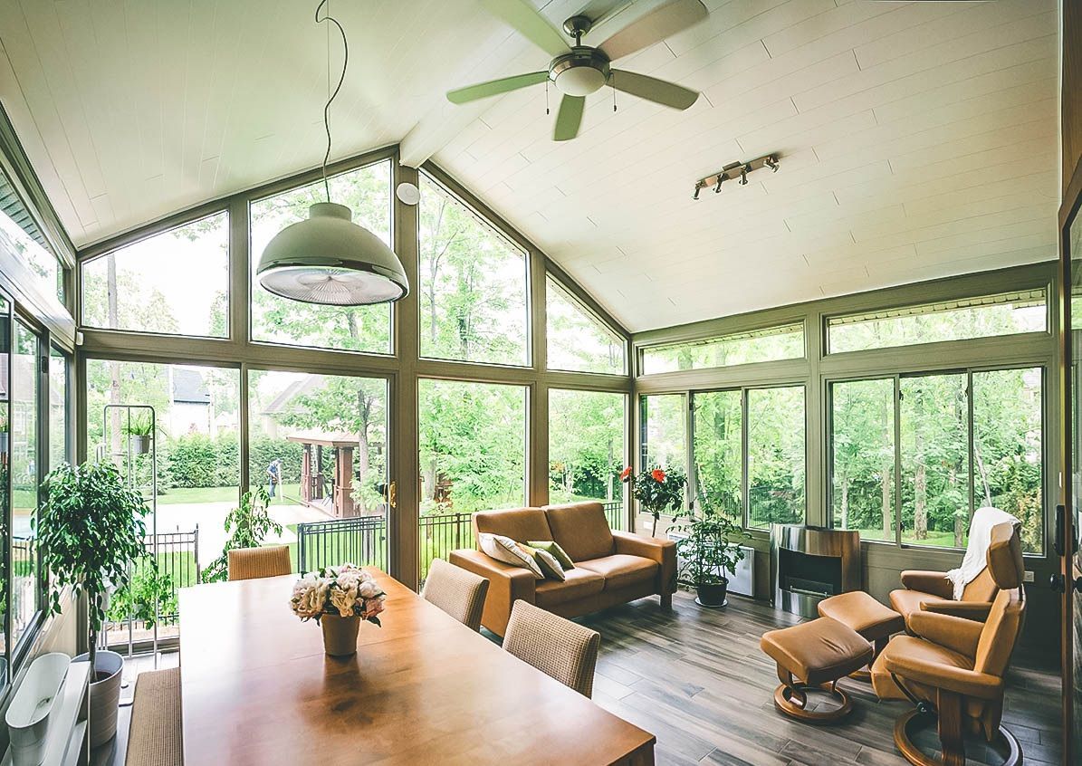 A living room with a lot of windows and a ceiling fan.