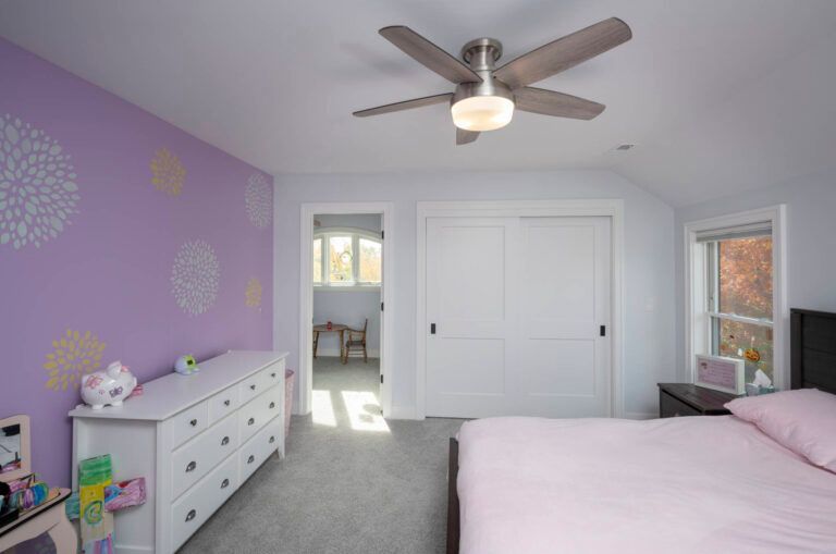 A bedroom with a bed , dresser , and ceiling fan.