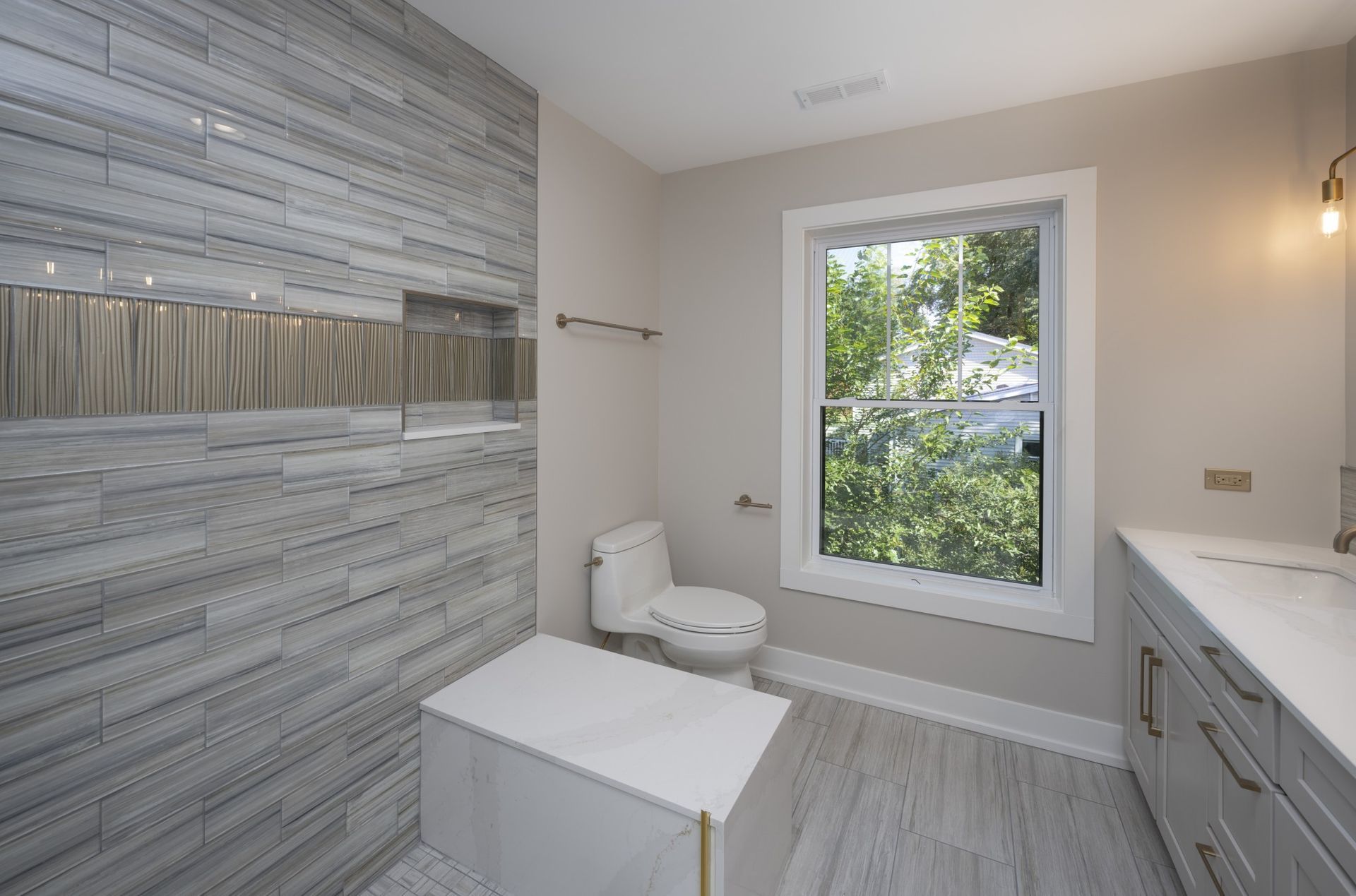 A bathroom with a toilet , sink , and window.