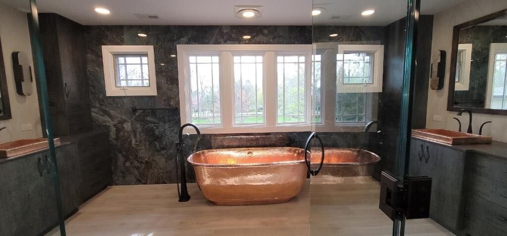 A bathroom with a copper bathtub and two sinks.