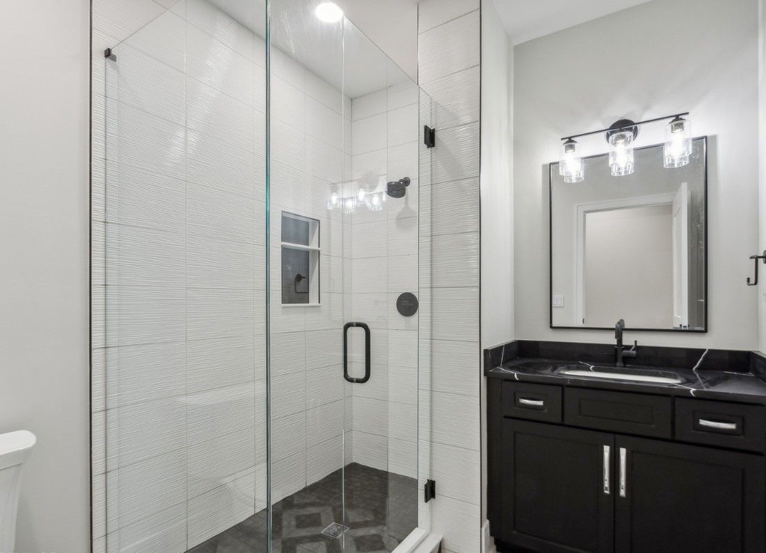 A bathroom with a walk in shower , sink and mirror.