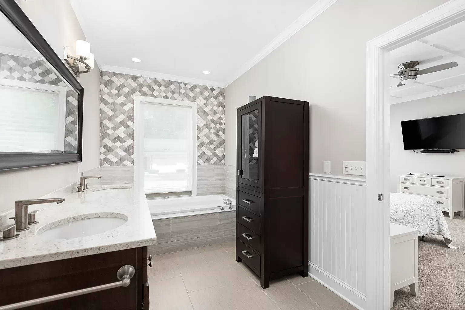 A bathroom with a sink , mirror , cabinet and tub.