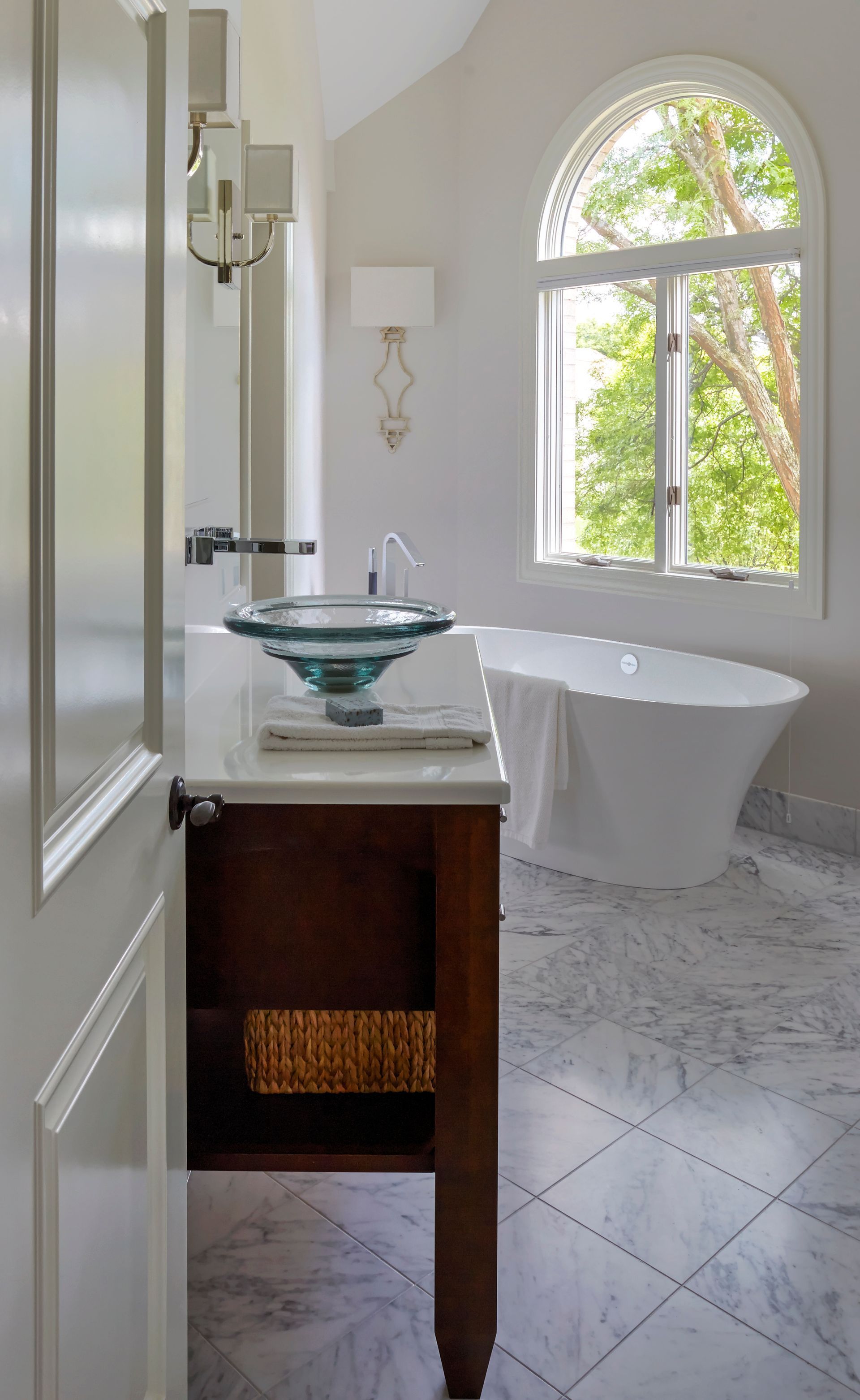 A bathroom with a tub , sink , and window.