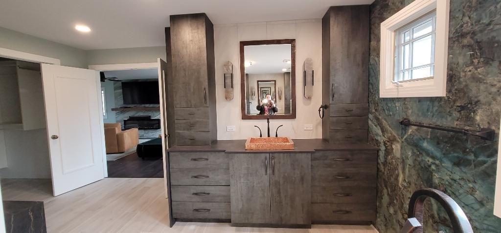 A bathroom with a sink , mirror and cabinets.