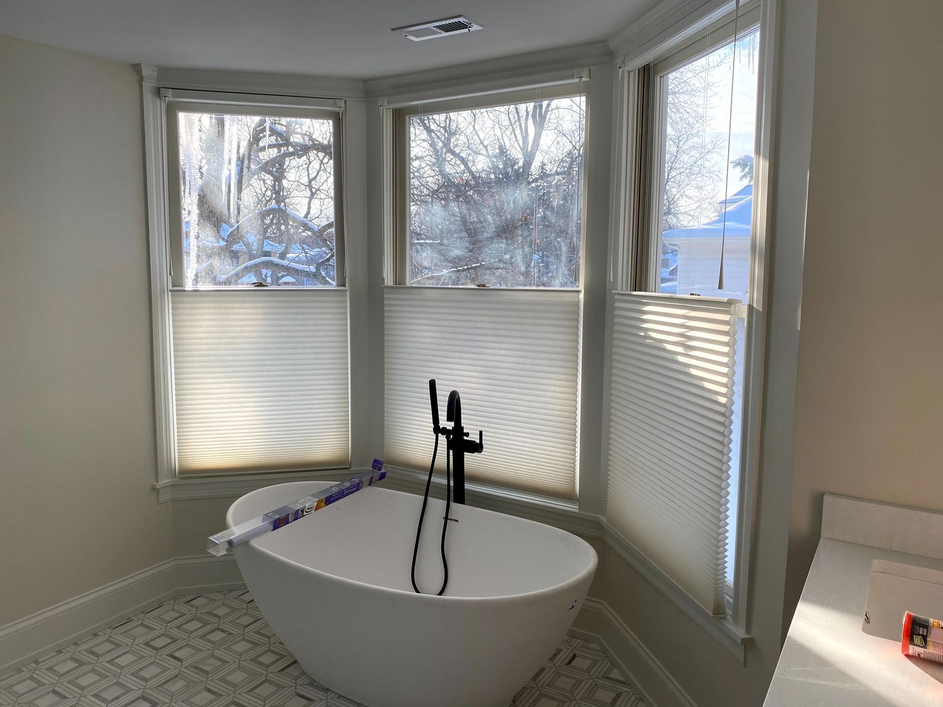 A bathroom with a bathtub and two windows.