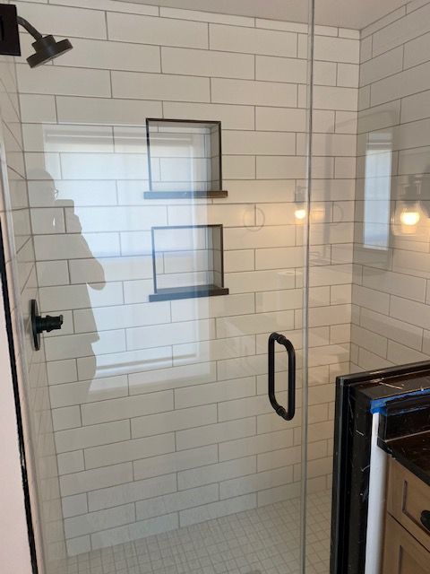 A bathroom with white tiles and a glass shower door