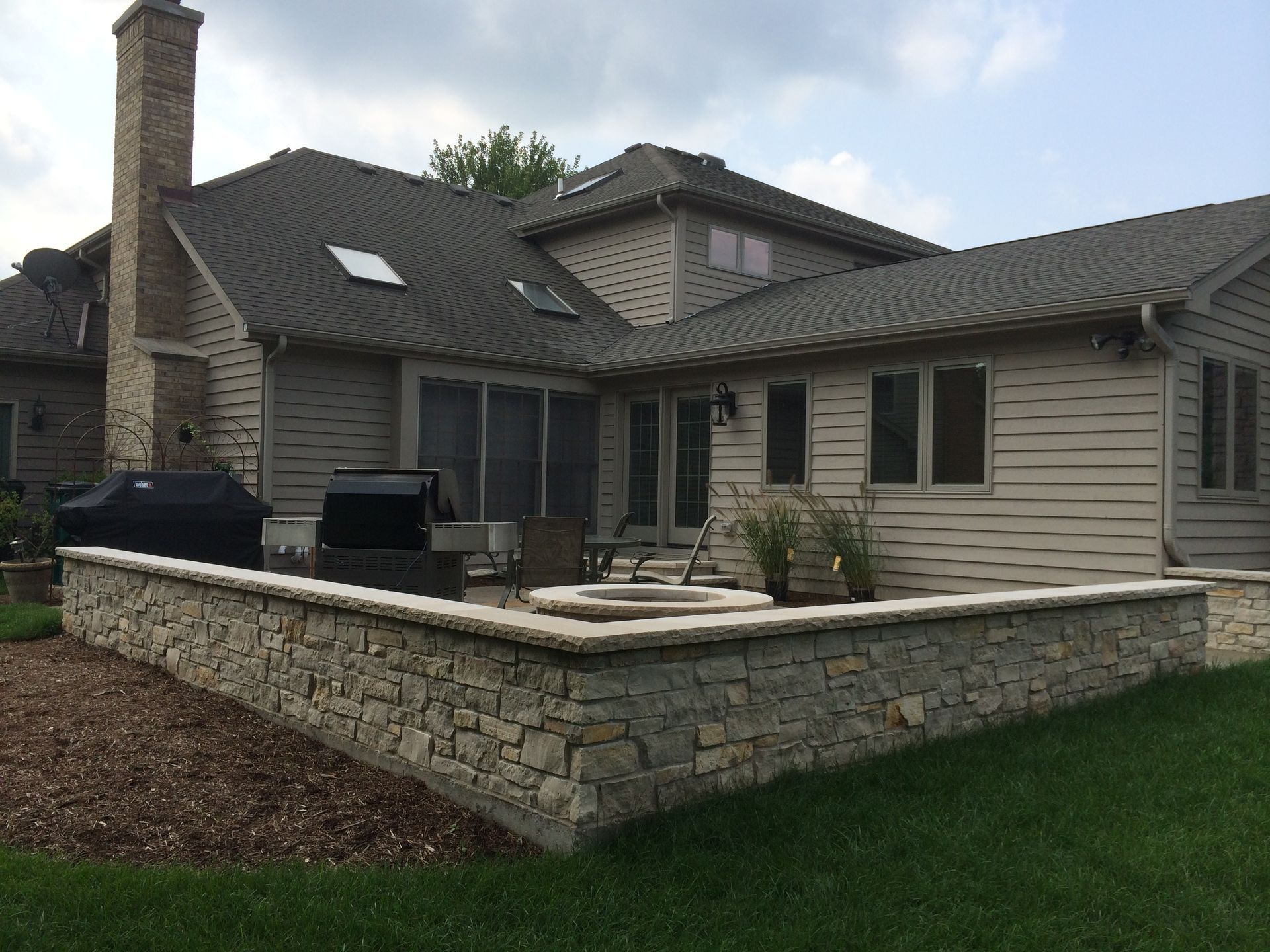 A large house with a stone wall in front of it.
