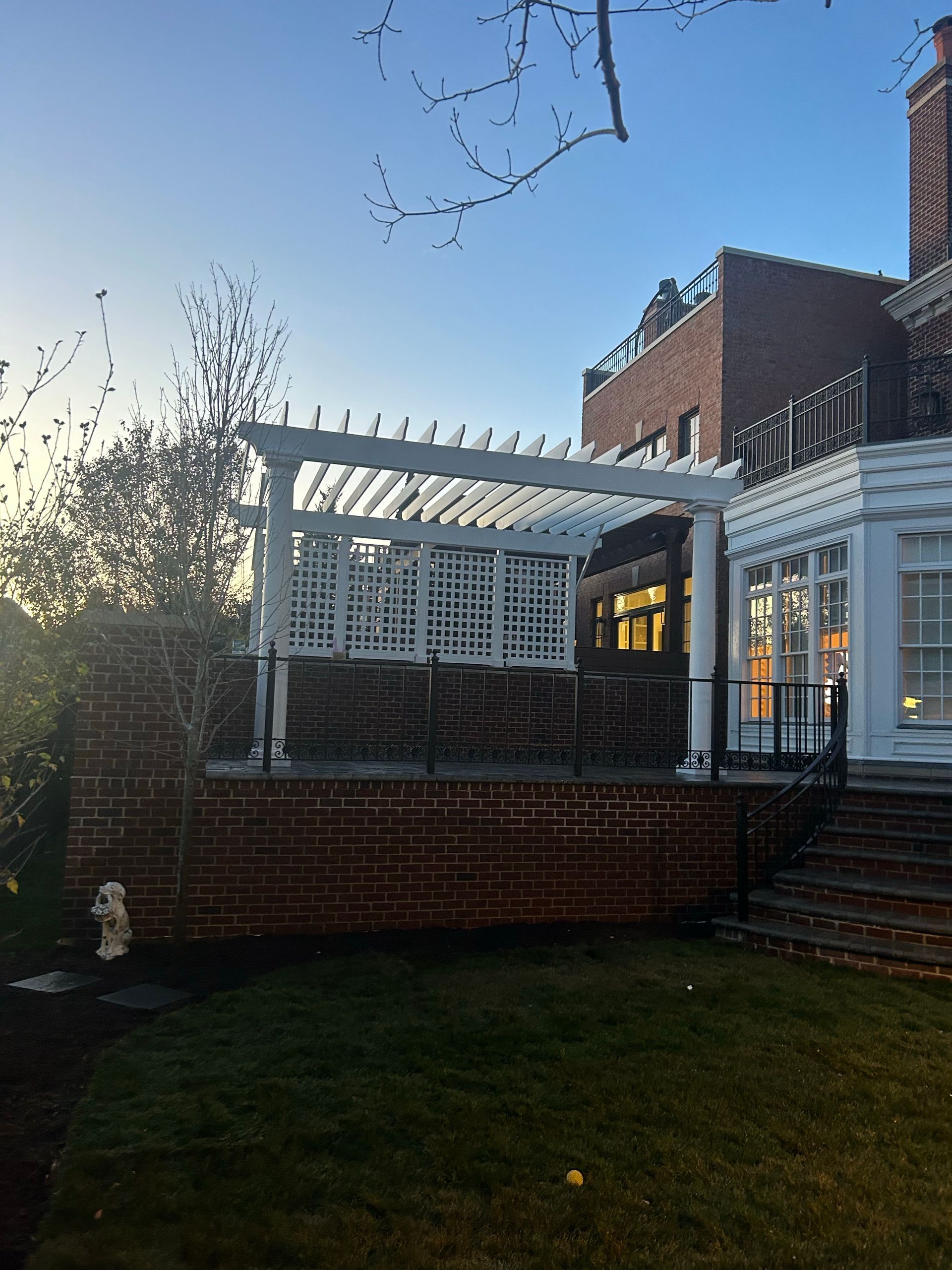 A white pergola is in the backyard of a house.