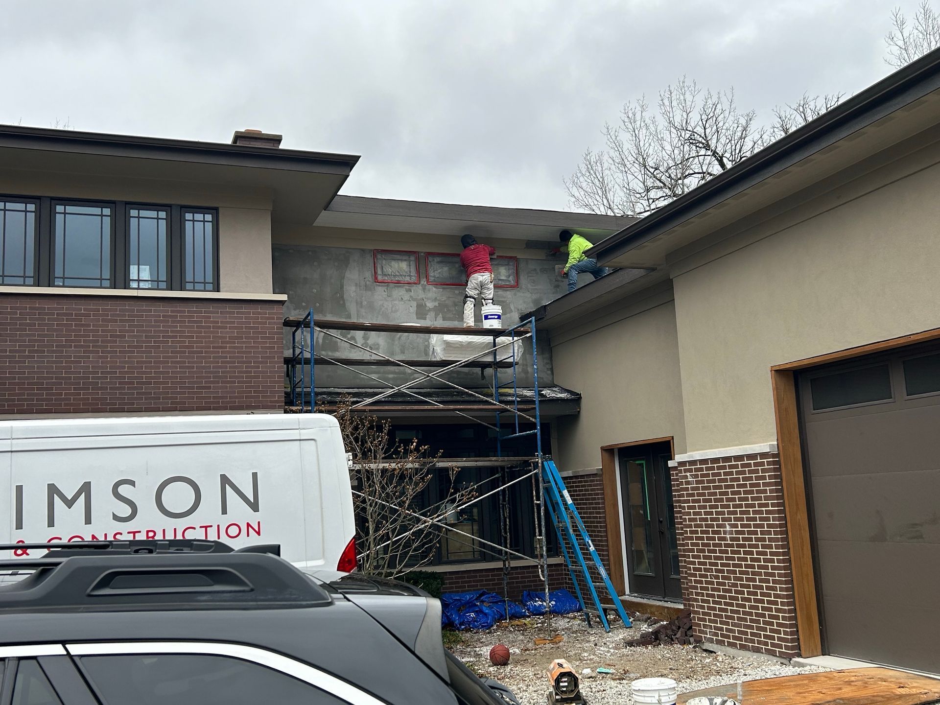 A white van is parked in front of a house under construction.