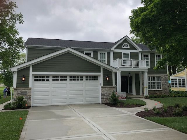 A large green house with a white garage door