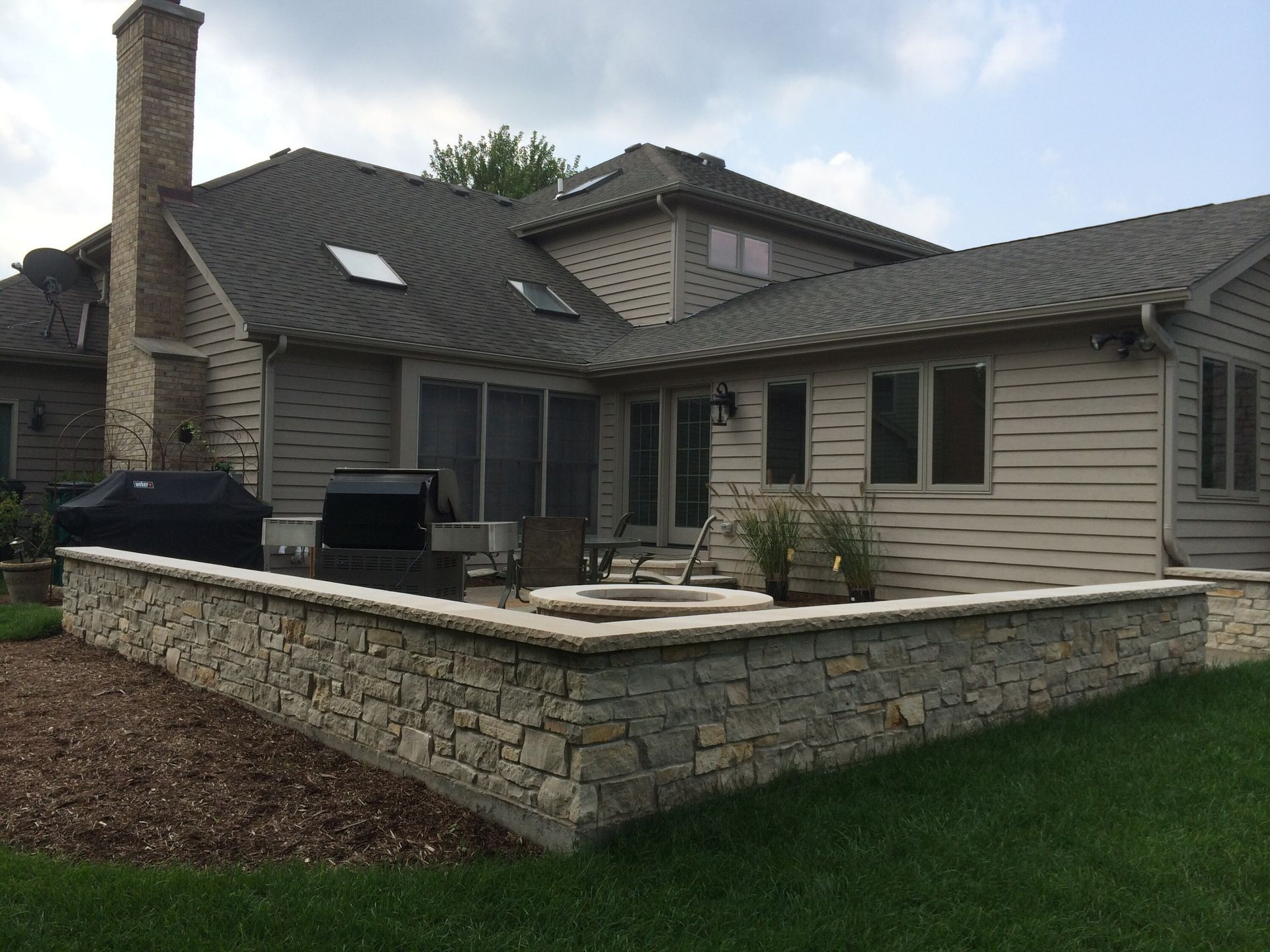 A large house with a stone wall in front of it.