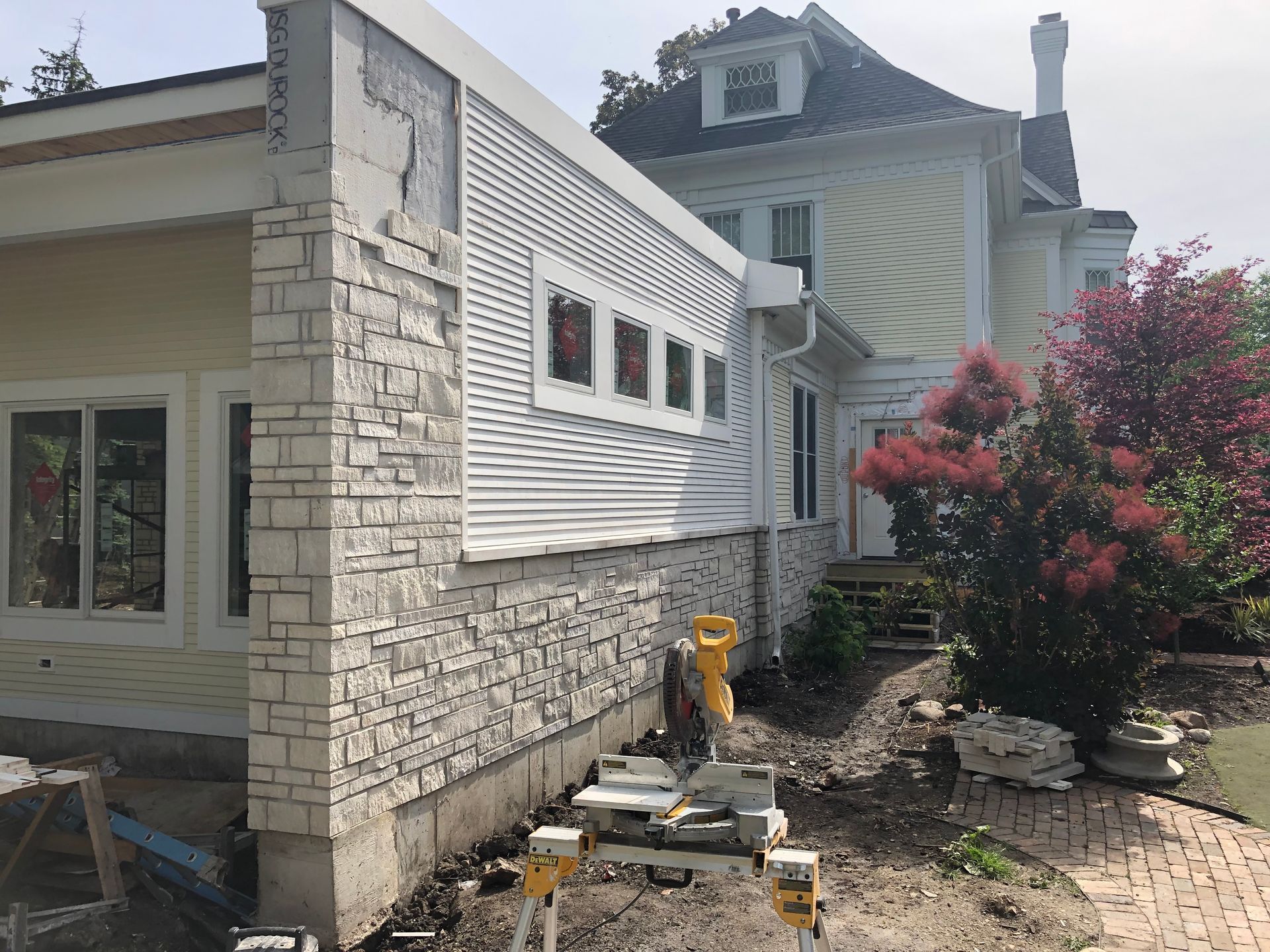 A house is being remodeled with a new siding and a brick wall.