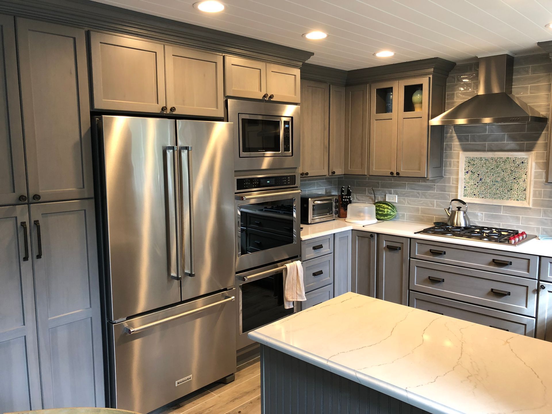 A kitchen with stainless steel appliances and gray cabinets.