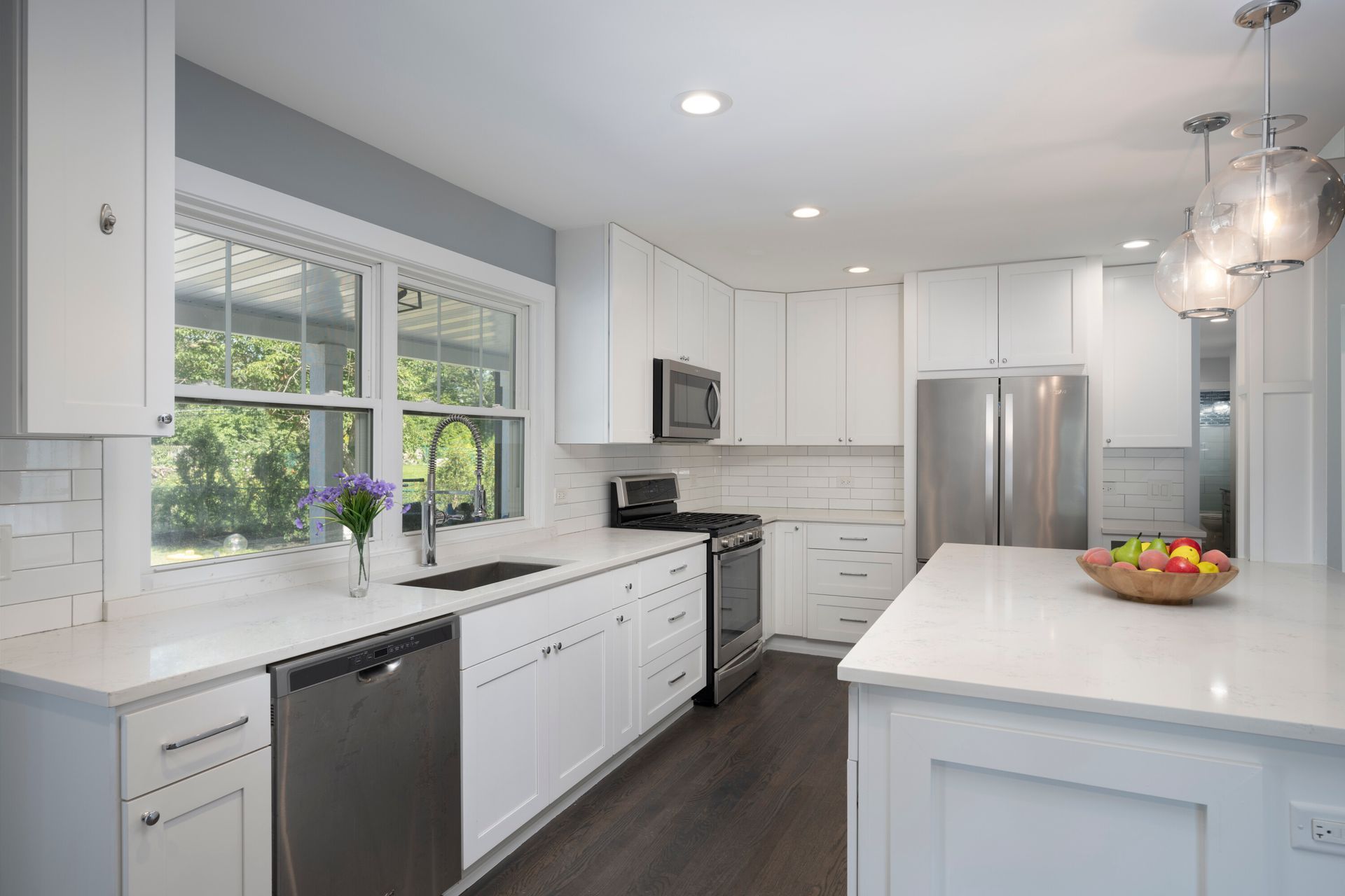 A kitchen with white cabinets , stainless steel appliances , and a large island.