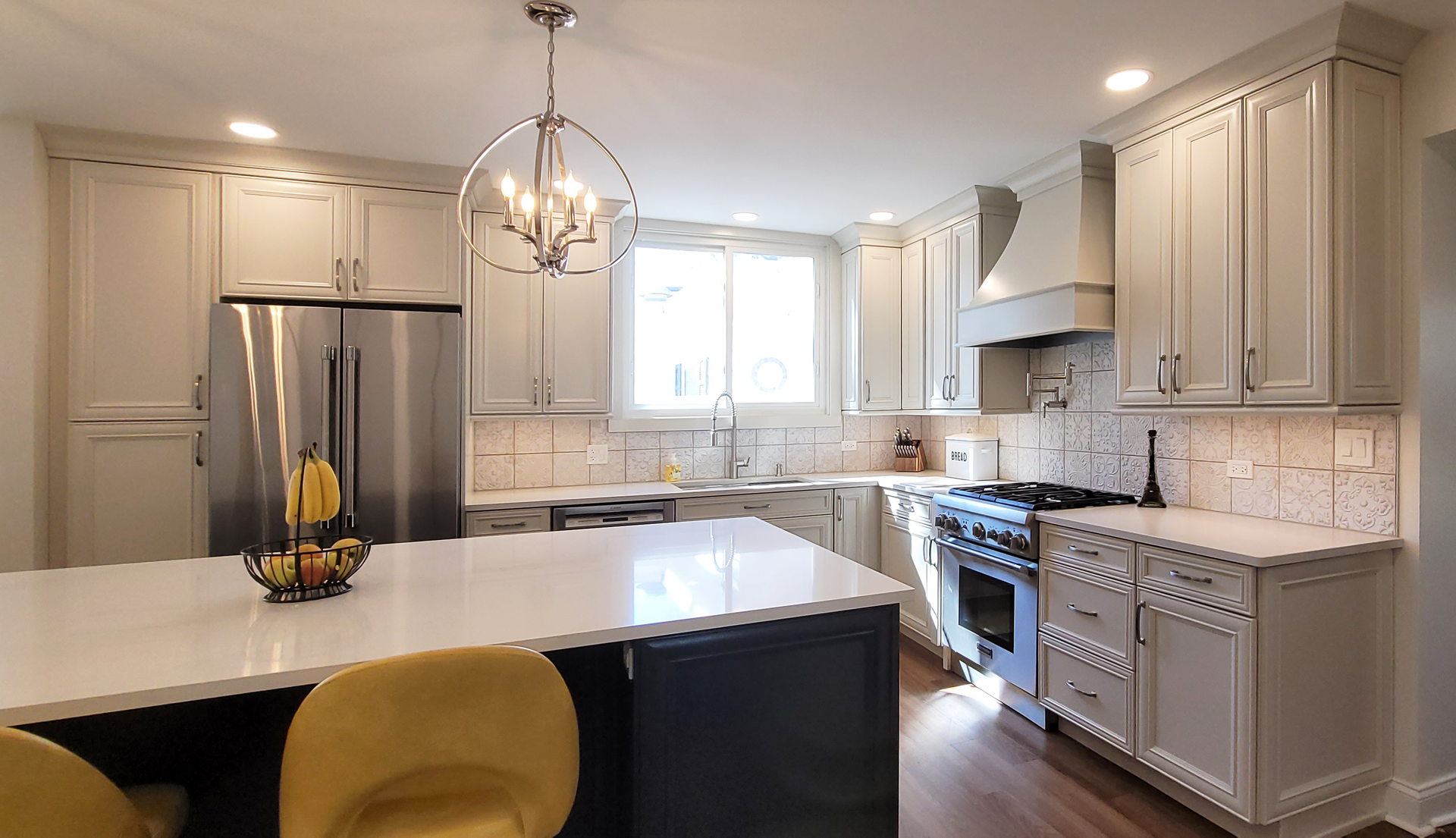 A kitchen with white cabinets , stainless steel appliances , and a large island.
