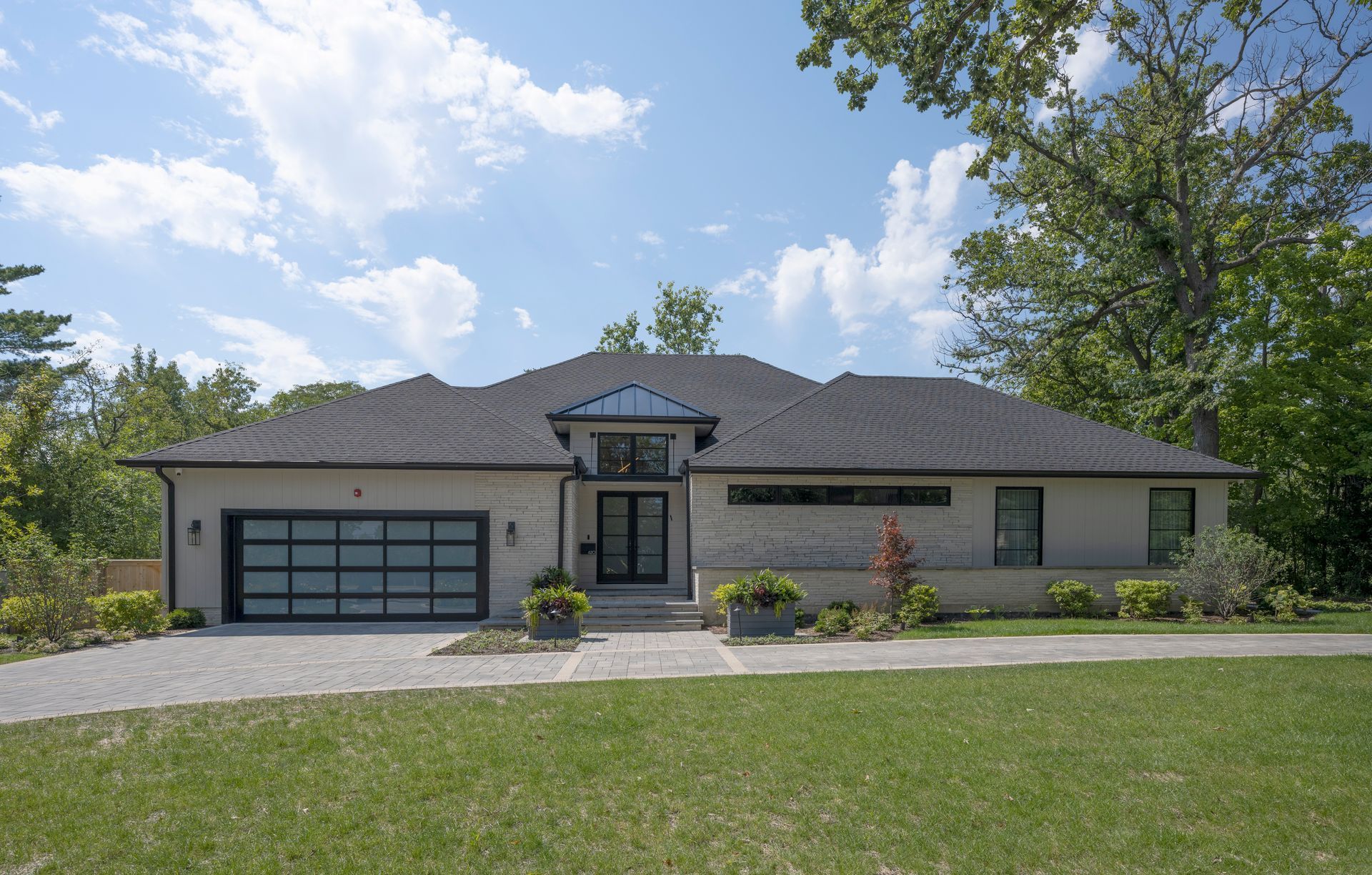A large house with a black garage door is sitting on top of a lush green lawn.