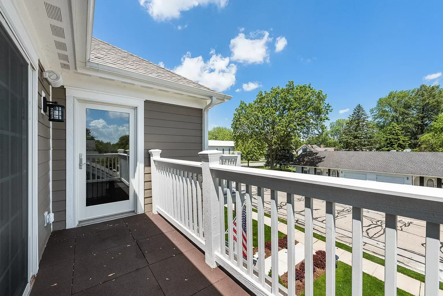 A balcony with a white railing and a sliding glass door.