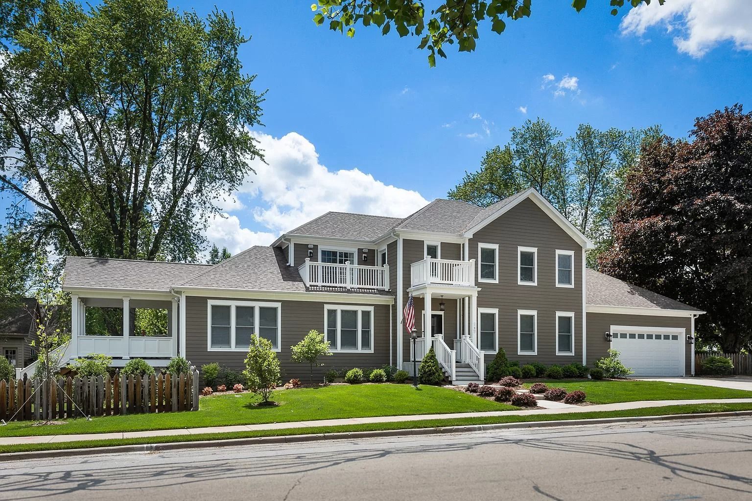A large house with a lot of windows is sitting on a lush green lawn.