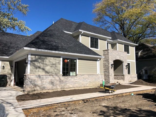 A large house with a black roof is being built.